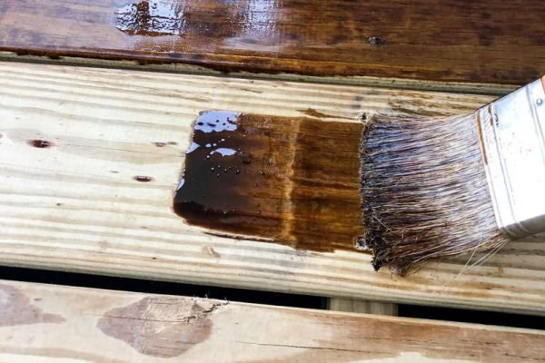 staining-the-deck-with-pine-cone-colored-water-seal-to-protect-it-from-damaging-rain-and-water-to_t20_NxyQQQ